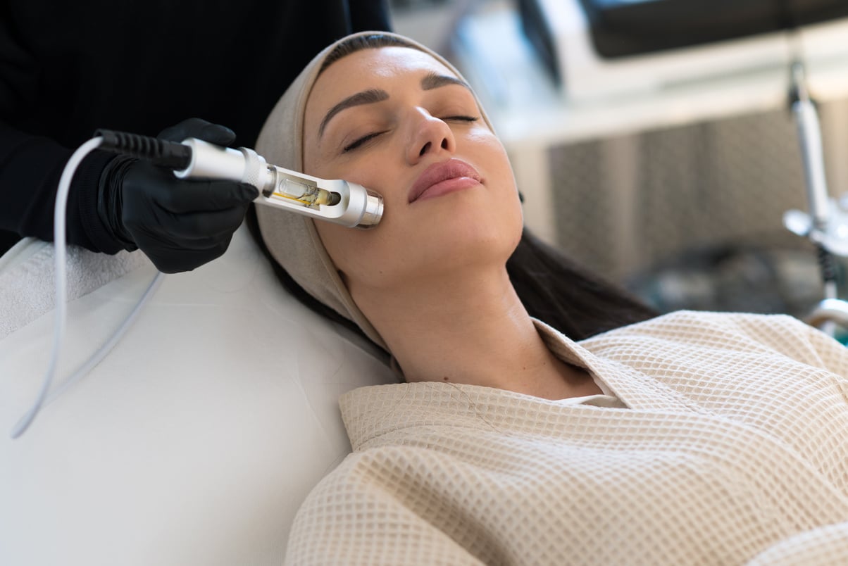 Professional female cosmetologist doing Hydrafacial procedure in Cosmetology clinic. Stock photo